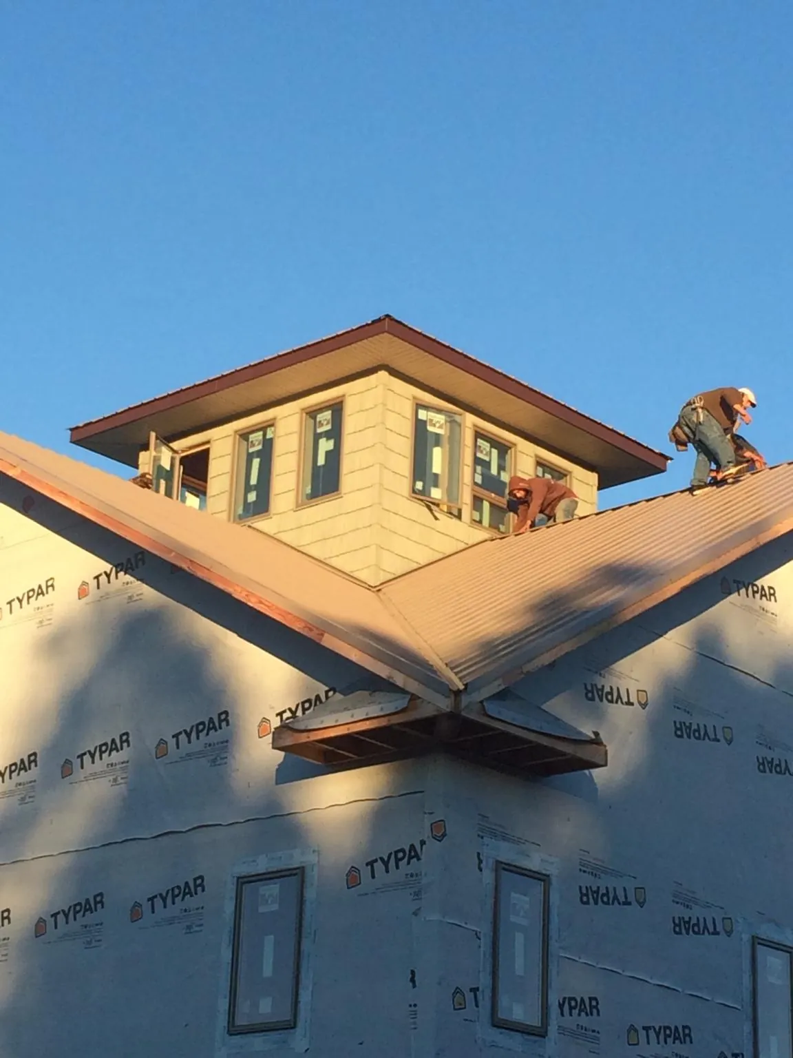 Roofers working around a rooftop cupola on a new metal roof at sunset — Roof Waterproofing in Geneva by Roofing Brothers